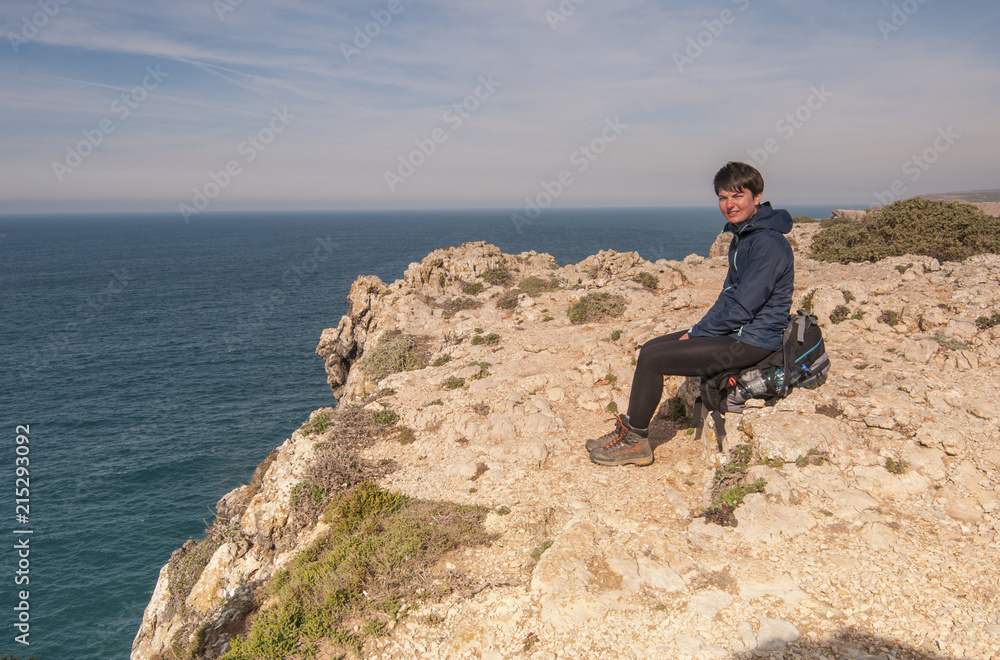 The girl is seating on the coast of the Atlantic ocean, cliffs, Portugal