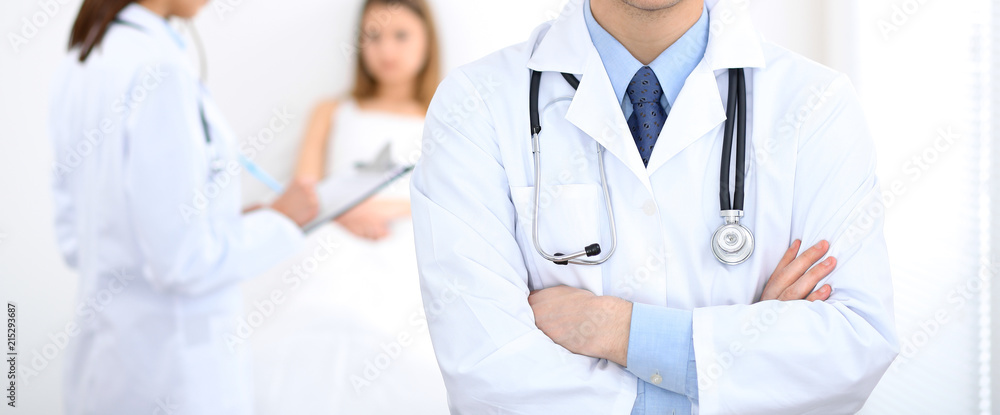 Doctor man standing straight in hospital. Closeup of stethoscope at practitioner breast. Medicine and health care concept Doctor man standing straight in hospital. Closeup of stethoscope at practitioner breast. Medicine and health care concept
