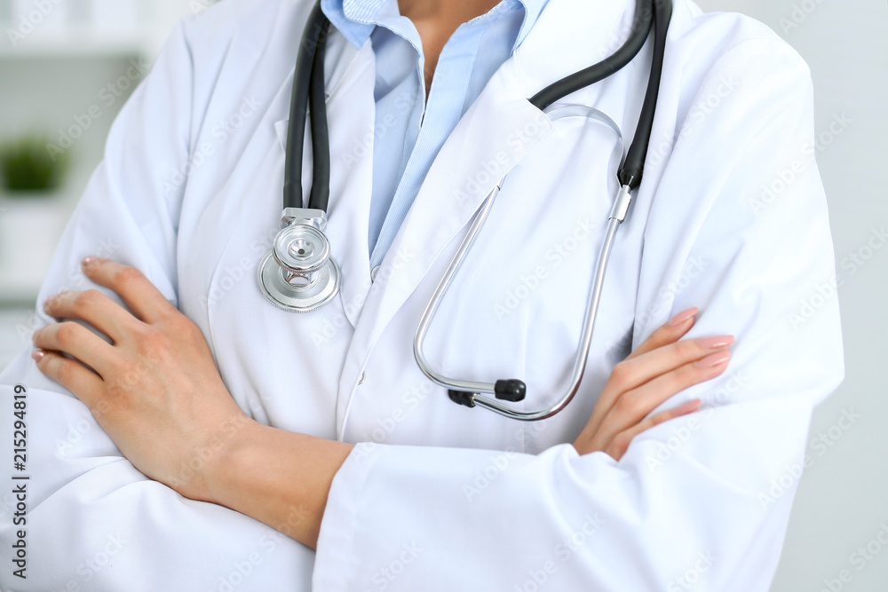 Closeup of doctor woman standing with arms crossed at hospital. Health care, insurance and help concept Closeup of doctor woman standing with arms crossed at hospital. Health care, insurance and help concept