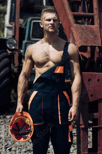 Metal worker. Metal worker rest at heavy machinery. Handsome metal worker in working uniform. Strong metal worker with muscular arms and torso