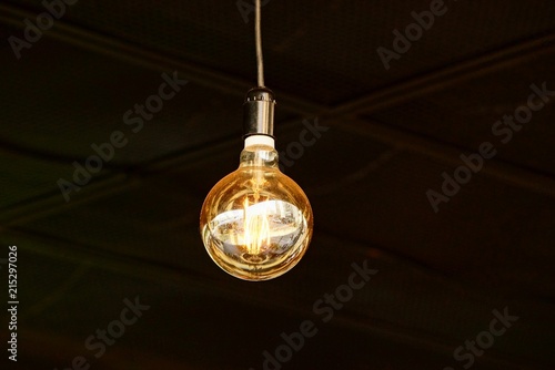 large luminous round light bulb on a cord in a dark room photo