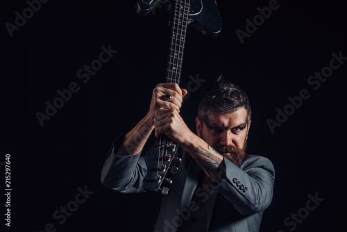 Concert concept. Hipster with musical instrument on concert tour. Bearded man hold guitar in hands at concert. Punk rock music concert. My music is all I got