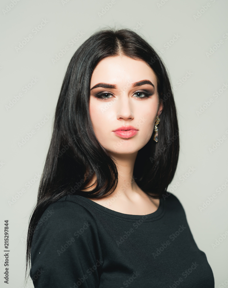 Beautiful young woman with long black hair posing in studio. Brunette smoky eyes isolated on gray background Beautiful young woman with long black hair posing in studio. Brunette smoky eyes isolated on gray background