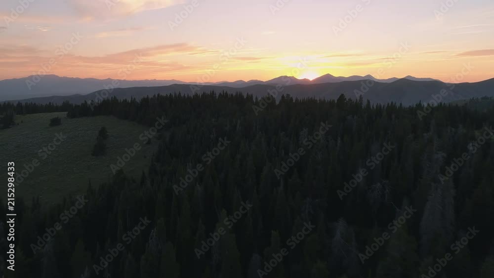 Aerial view flying over forest on rolling hills towards sunset in the Idaho mountains. Aerial view flying over forest on rolling hills towards sunset in the Idaho mountains.