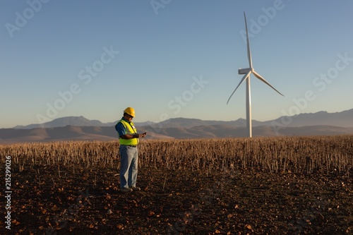 Engineer using mobile phone at wind farm photo