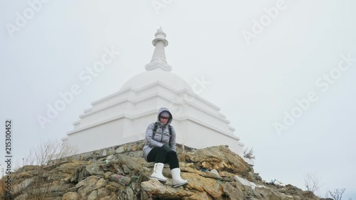 Travel of woman on ice of Lake Baikal. Close unique buddhist stupa burkhan monument symbol mystical historic ritual island Ogoi landscape mountains shamanic worship. Trip to winter island. Hiker wears photo