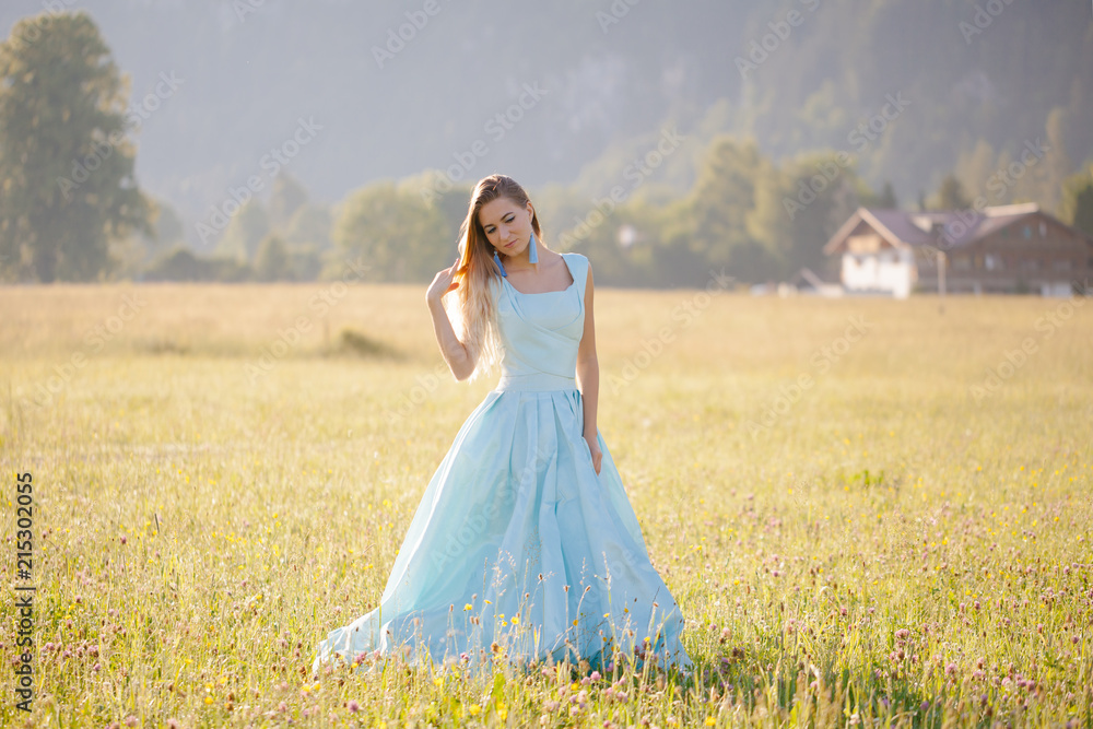 blond girl in blue dress infront of the castle