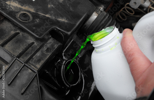 Pouring flourescent green antifreeze into a black engine