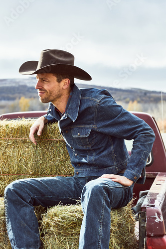 cowboy sitting on his hay in the back of a truck photo