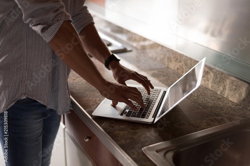 Man using laptop in kitchen at home photo
