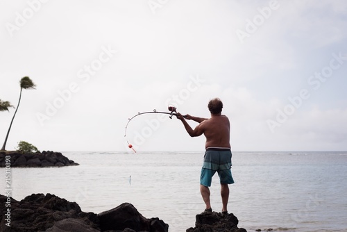 Fisherman fishing on a beach photo