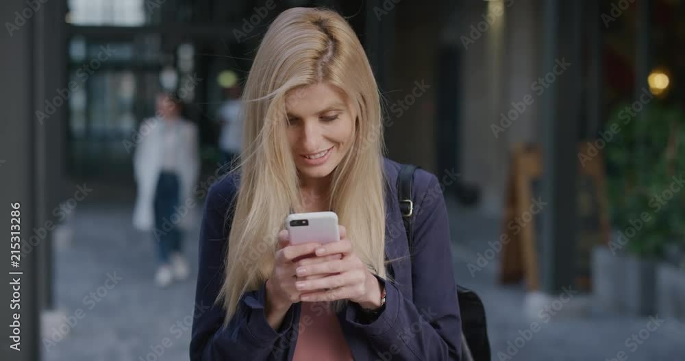 portrait young beautiful blonde woman using smartphone in city enjoying relaxed urban lifestyle browsing online messages texting on mobile phone slow motion portrait young beautiful blonde woman using smartphone in city enjoying relaxed urban lifestyle browsing online messages texting on mobile phone slow motion