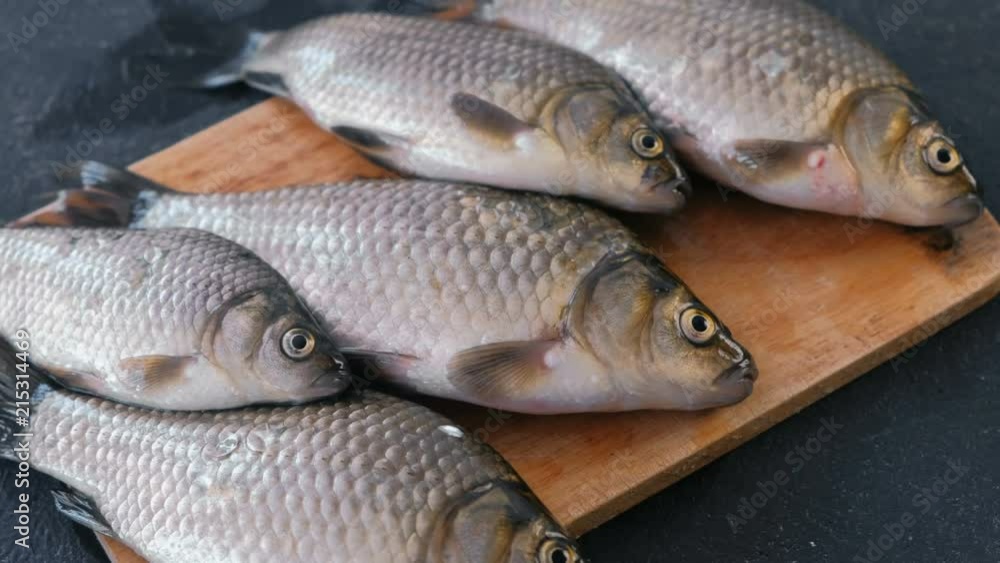 Cooking fish. Fresh small carps on the table on a wooden Board close-up. Cooking fish. Fresh small carps on the table on a wooden Board close-up.