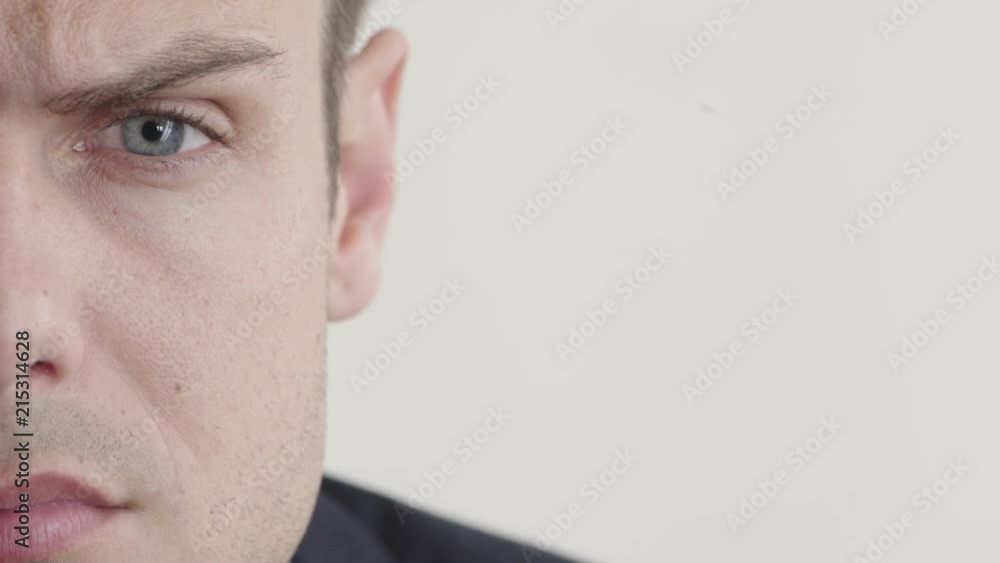 close up young man making faces looking angry expression showing emotion on white background half face close up young man making faces looking angry expression showing emotion on white background half face