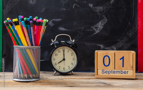 September 1st date, alarm clock and colorful pencils on blackboard background