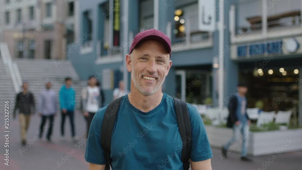 portrait of mature attractive caucasian tourist man wearing hat looking at camera smiling city background portrait of mature attractive caucasian tourist man wearing hat looking at camera smiling city background