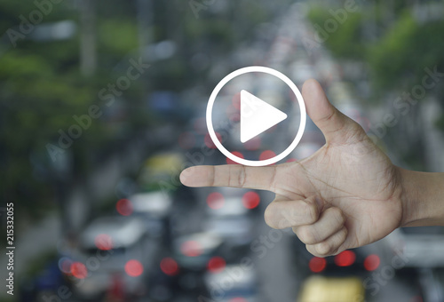 Play button icon on finger over blur of rush hour with cars and road, Business music online concept