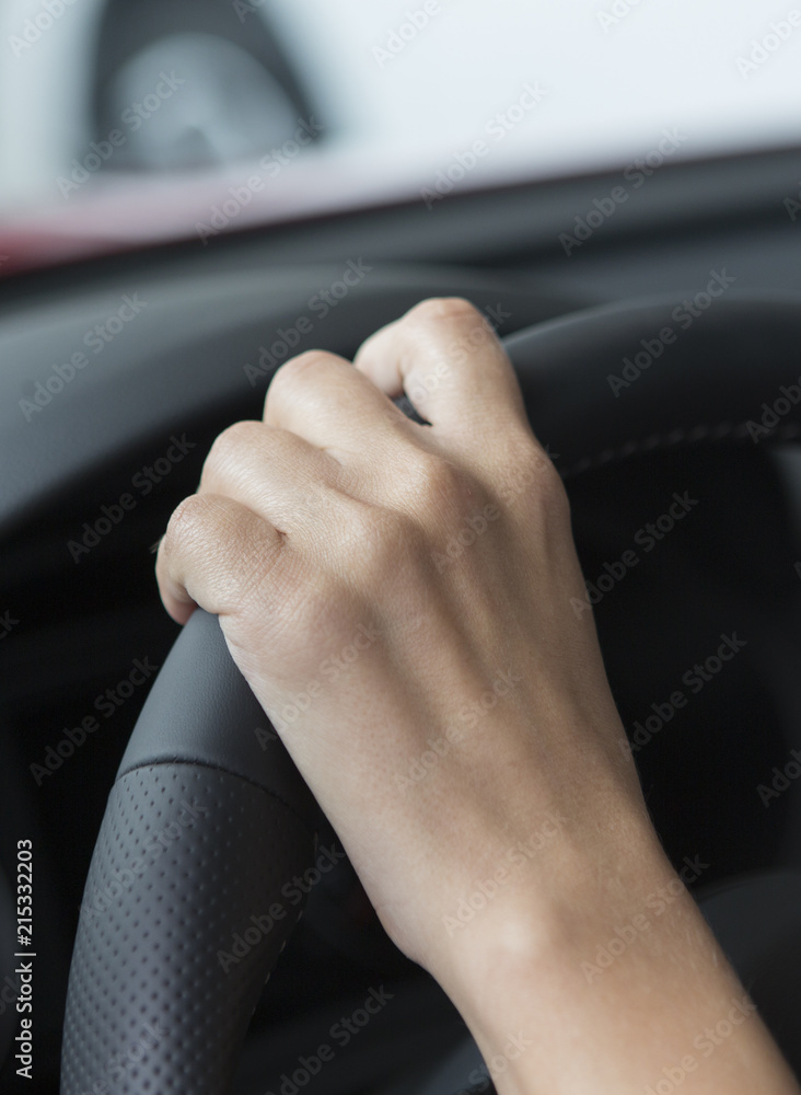 The hand of a girl with a stylish manicure lies on the handlebars in a saloon car.