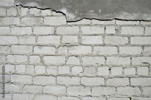 Wall with partially removed plaster in the form of figured drawing of a brick texture. Background