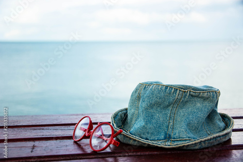 Red glasses and hat Placed on a wooden table by the sea.
