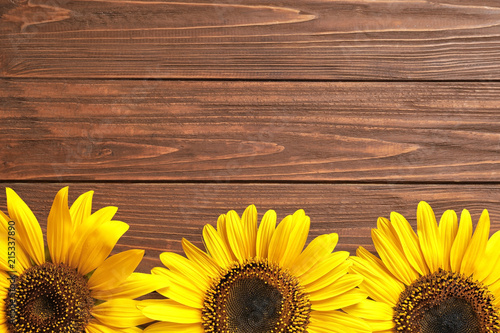 Fototapeta Naklejka Na Ścianę i Meble -  Beautiful bright sunflowers on wooden background, top view