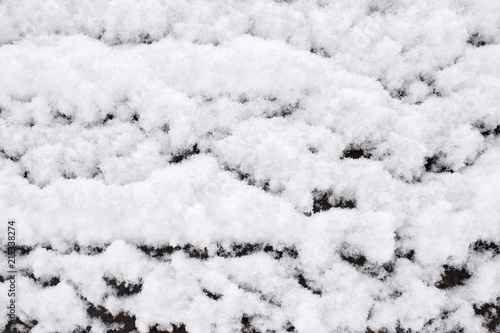 Airy texture of fluffy snow lying on a wooden bench. Background
