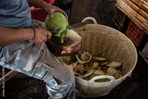 man worker chopped a coconut with basket in market