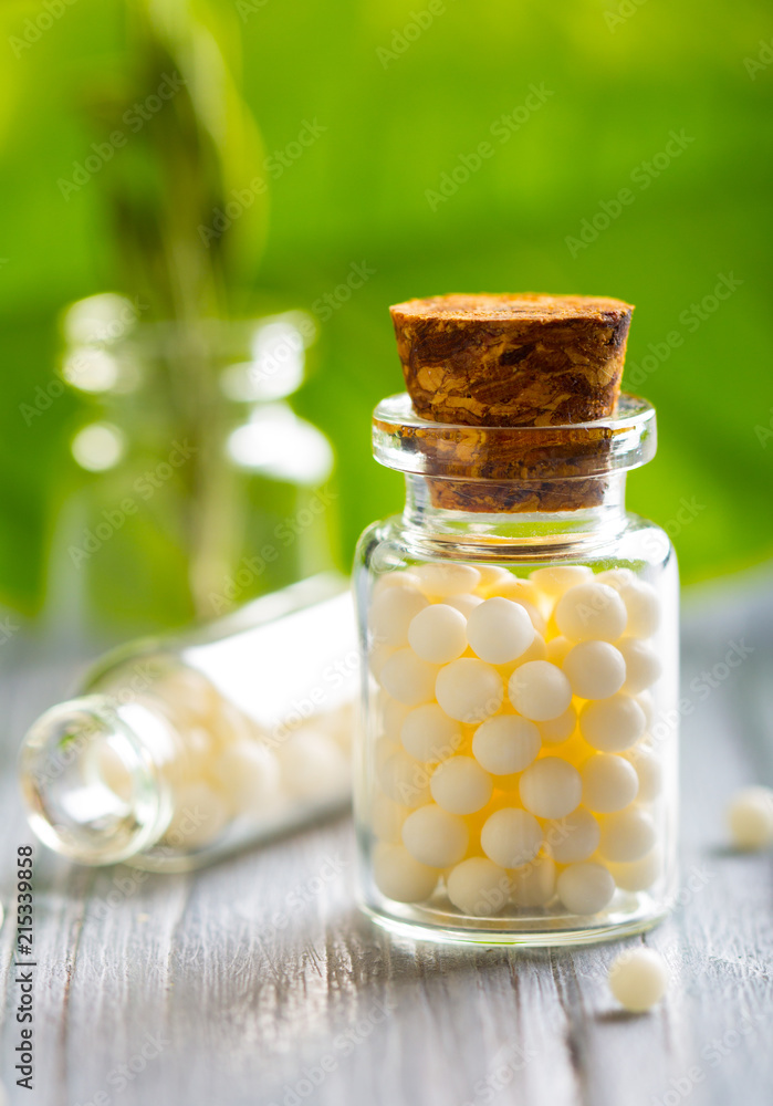 Homeopathy pills bottle wooden eco green leaf background Homeopathy pills bottle wooden eco green leaf background