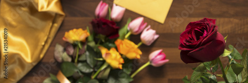 envelope and bouquet of flowers on wooden table
