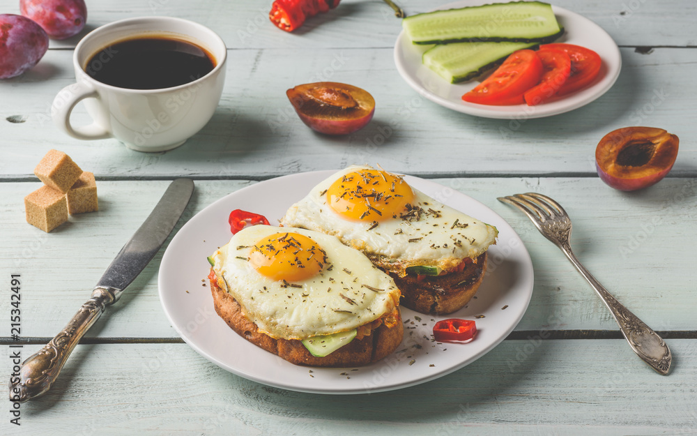 Breakfast toasts with vegetables and fried egg on white plate, cup of coffee and some fruits over wooden background. Clean eating food concept. Breakfast toasts with vegetables and fried egg on white plate, cup of coffee and some fruits over wooden background. Clean eating food concept.