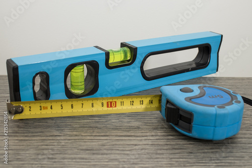 Tools, blue bubble level and measuring tape on a decorated wood table