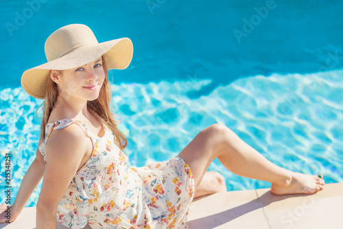 Summertime in pool. Young woman with floppy hat and at pool.