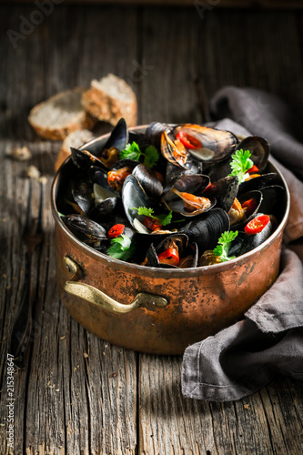 Tasty mussels served with wholemeal bread on wooden table