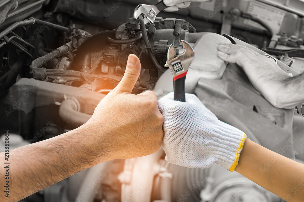 Mechanic hand checking and fixing a broken car in  garage.hand of mechanic with thumbs up and tool