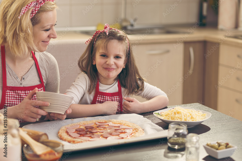 Little girl putting salami on the pizza dough Little girl putting salami on the pizza dough
