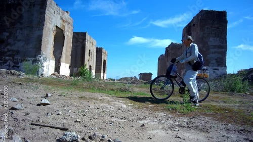 a man with a bicycle is walking in front of a ruined building