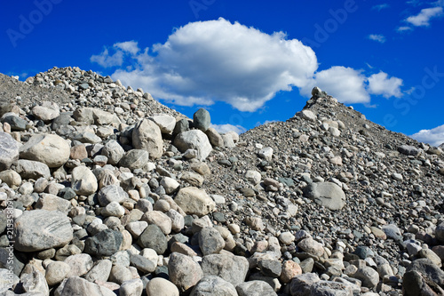 Heap of stones and gravel against blue sky and clouds. © ekim