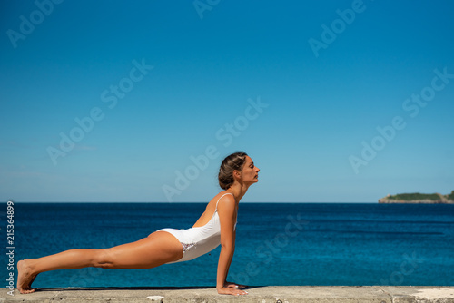 Young woman practicing yoga on a beach © ivanaculafic