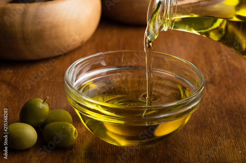Fotografi Extra virgin olive oil flowing from it's bottle