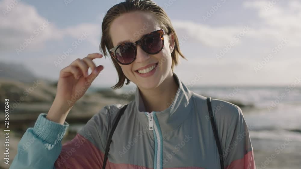portrait of attractive young woman smiling at beach removes sunglasses portrait of attractive young woman smiling at beach removes sunglasses