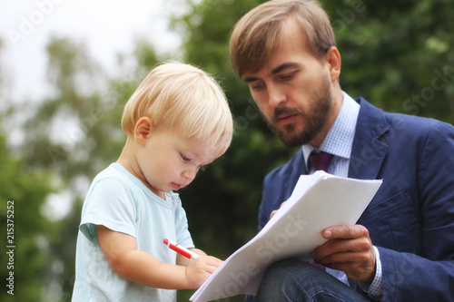 father gives financial documents to his son, baby writes papers or business contract