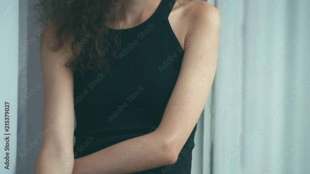 Young woman near window, looking sad,turns head and smile, shallow depth of field Young woman near window, looking sad,turns head and smile, shallow depth of field