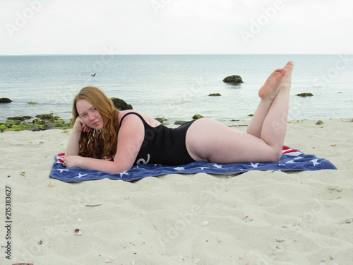Canvas Print Side view of a beautiful redheaded woman wearing a black one-piece bathing suit