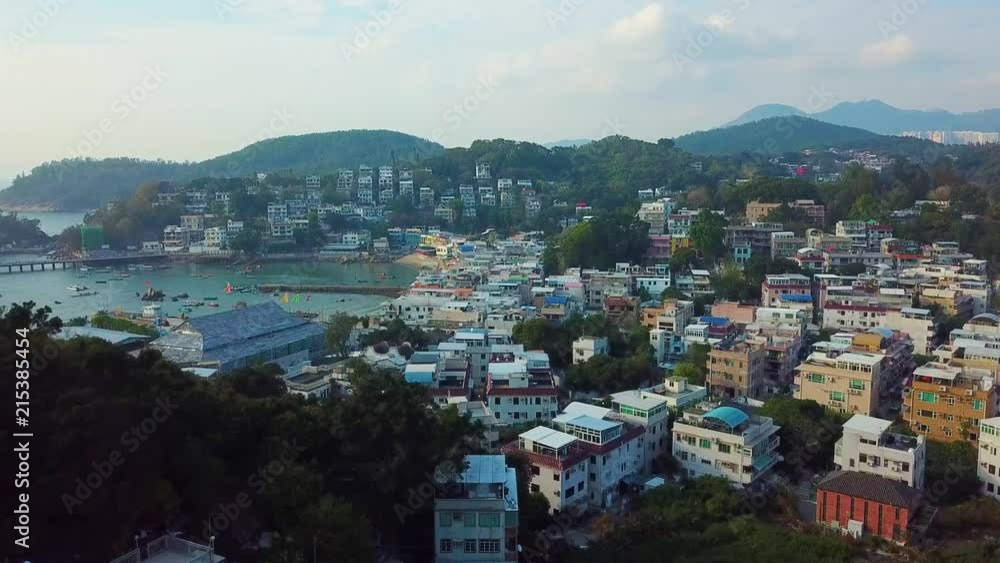 Drone shot flying over inland houses on Lamma island with water and mountains in the distance, Hong Kong Drone shot flying over inland houses on Lamma island with water and mountains in the distance, Hong Kong