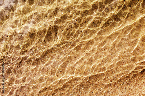 Soft wave of water on sandy beach, background.