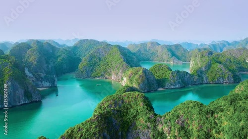 Wide aerial view of islets in Ha Long Bay Vietnam, with vivid green mossy hills and turquoise blue waters photo