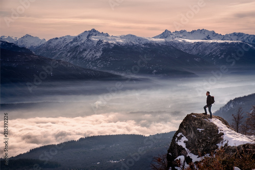 Man hiker looking mountain landscape with fog standing on a rock in Patagonia Argentina photo