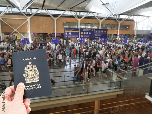 Hand handing Canadian passport at airport custom counters, immigration concept