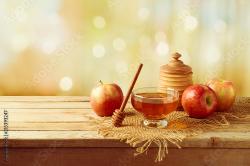 Honey and apples on wooden table.