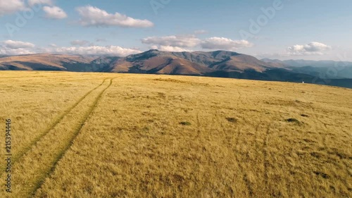 Flying forward to Tarcului Carpathian mountains above a hill with offroad tracks. Aerial Drone shot. photo